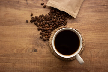 cup of coffee with beans on wooden table. For coffee background top view. Copy for your text.