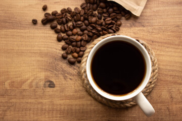 for coffee shop background. coffee in mug and coffee beans on wooden table. copy for your text. selective focus.