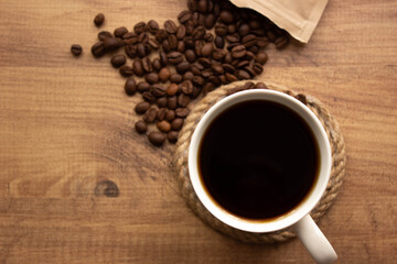 for coffee shop background. coffee in mug and coffee beans on wooden table. copy for your text. selective focus.