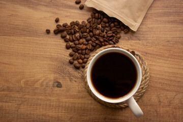 for coffee shop background. coffee in mug and coffee beans on wooden table. copy for your text. selective focus.