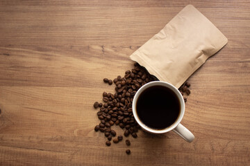 cup of coffee with beans on wooden table. For coffee background top view. Copy for your text.