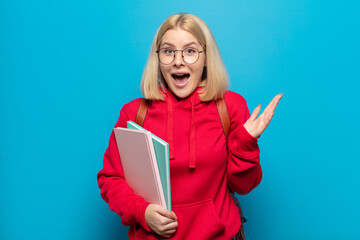 blonde woman feeling happy, excited, surprised or shocked, smiling and astonished at something...