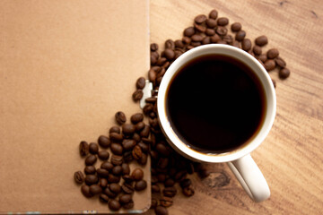 coffee mug, coffee beans, notebook, book on the wooden table for to do list nothing concept in cafe; top view. Coffee mug selective focusing for coffee shop vintage background . space for text.