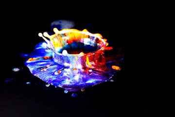 Drops of water colliding with powdered dye to create a multi coloured abstract droplet collision