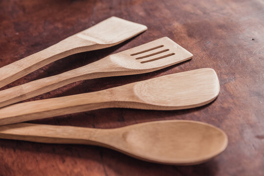 Detail photo of bamboo kitchen utensils and shovels arranged in a half moon, on a wooden background.