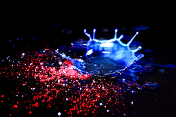 Drops of water colliding with powdered dye to create a multi coloured abstract droplet collision