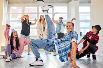 male dancer practicing brakedance moves, performing modern dance element, group of dancers next to him