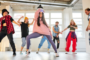 woman learning hip-hop choreography with her groupmates in dance studio, choreography concept