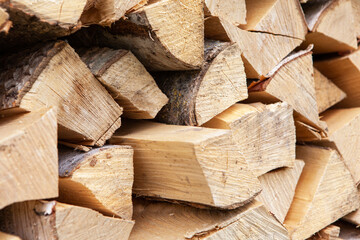 Background from stack of firewood from birch tree, for heating house, stacked in backyard, uncut wood, birch. Concept eco-friendly home heating during cold season. Soft selective focus. Horizontal