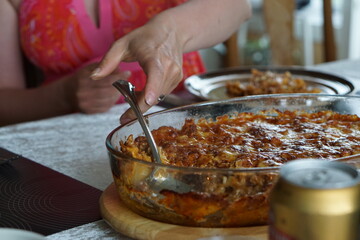 Woman about to put food on the plate, minced meat lasagne in a glass mold