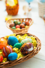 Fototapeta na wymiar Multi-colored Easter eggs in a basket on a white wooden background