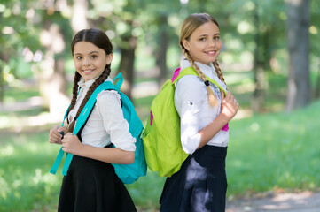 Happy children carry school bags in formal uniform outdoors, back to school