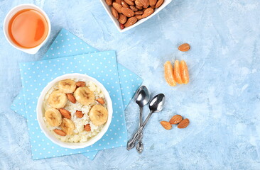 Useful breakfast with ingredients, flat lay, rice pudding with bananas, honey and almonds on a sunny table. Healthy and natural food concept, lifestyle, food for children,