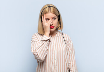 blonde woman feeling bored, frustrated and sleepy after a tiresome, dull and tedious task, holding...