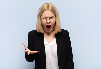 blonde woman looking angry, annoyed and frustrated screaming wtf or what’s wrong with you