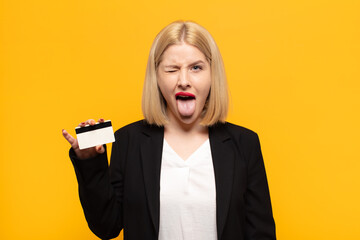blonde woman with cheerful, carefree, rebellious attitude, joking and sticking tongue out, having...