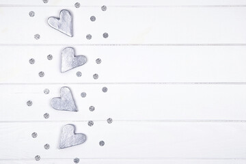 Top view of silver gray decorative hearts with confetti over white planked wooden background. Valentines day love concept.Copy space.
