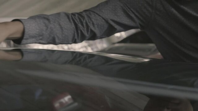 Mano de un joven aplicando un producto a un parabrisas