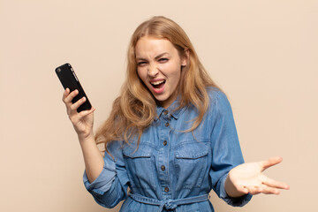blonde woman looking angry, annoyed and frustrated screaming wtf or what’s wrong with you