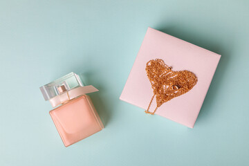 A gift for Valentine's Day. Perfume and a box with a gold chain on a blue background. Chain in the shape of a heart.