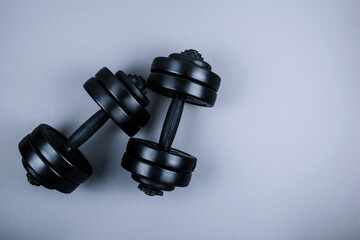 Top view of black  dumbbells  weights on pastel grey background. Flat lay. Fitness or bodybuilding sport training concept. Copy space.