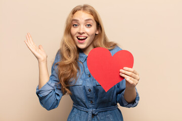 blonde woman feeling happy, excited, surprised or shocked, smiling and astonished at something...