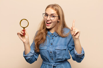 blonde woman feeling like a happy and excited genius after realizing an idea, cheerfully raising...