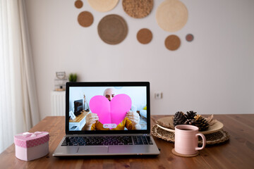 Connecting from the internet with laptop, man romantically shows his love with heart in hand. new normally living distant love.
