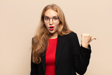blonde woman looking astonished in disbelief, pointing at object on the side and saying wow,...