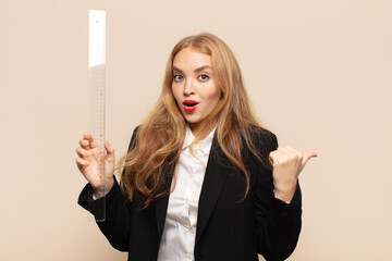 blonde woman looking astonished in disbelief, pointing at object on the side and saying wow,...