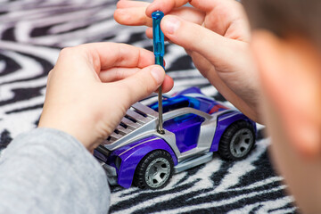 Small child boy holding screwdriver, fixing broken toy.  A boy fixing toy car with screwdriver