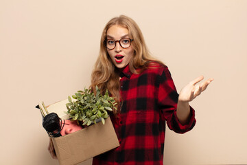blonde woman feeling extremely shocked and surprised, anxious and panicking, with a stressed and...