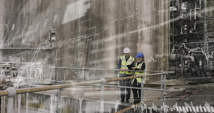 Industrial workers inspecting industrial plant using digital tablet, wearing protective workwear and pointing