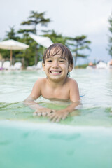 Cute little boy kid child splashing in swimming pool having fun leisure activity