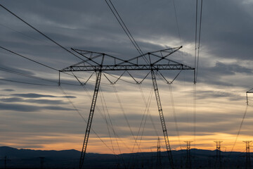 Electric poles in a field during the sunset