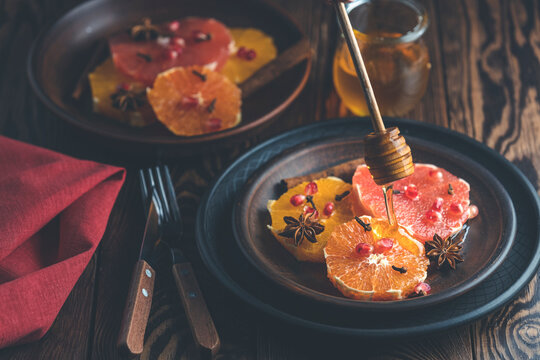 Orange dessert with wine honey or maple syrup and ginger spice, decorated pomegranate berries. Wonderfully sweet, rich and fresh food. Dark rustic background