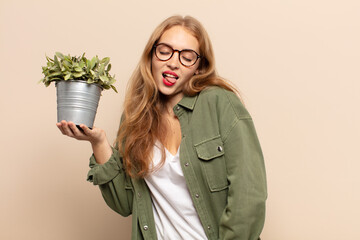blonde woman with cheerful, carefree, rebellious attitude, joking and sticking tongue out, having...