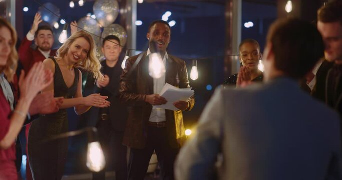 Multi-ethnic people celebrate corporate holiday party. Afro-american young boss leader making speech for his audience.