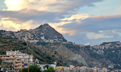 view of a town on a hillside, a town by the sea in Italy, buildings located on hills, light breaking through the clouds