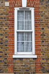window with floral curtains on a brick wall house