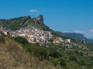 Fototapeta na wymiar Cityscape of old pictoresque village Ulassai with limestone climbing rock and green vegetation and mountains at countryside of Sardinia island. Summer sunny day. Province Nuoro, Sardinia, Italy