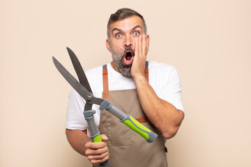 adult man feeling shocked and scared, looking terrified with open mouth and hands on cheeks