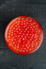 Red caviar, on black wooden table background, top view flat lay