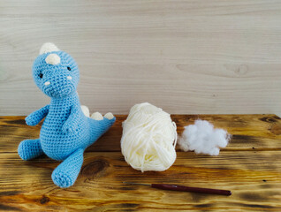 Hand-made crochet blue toy tyrannosaurus on wooden background