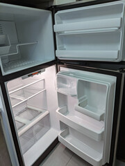 empty, modern refrigerator and freezer with opened doors. Inside of a clean fridge with plastic shelves