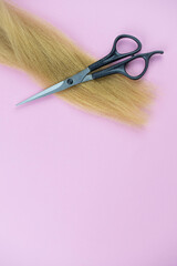 Professional hair dresser tools with copy space on trendy pink background. Stylist equipment set. Scissors and hair curls flat lay top view.