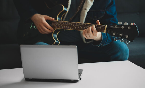 Teacher shows how to play the guitar. Remote online lesson.