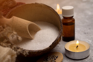 Coconut bowl with sea salt, essential oil and lighted candles. Massage, relaxation and spa concept.