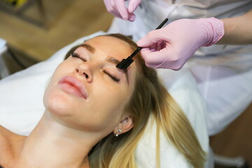 beautician makes eyebrow care for woman. eyebrow brushing close up