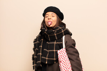 hispanic woman with cheerful, carefree, rebellious attitude, joking and sticking tongue out, having...
